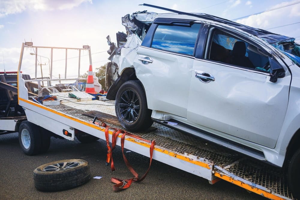 Emergency vehicle recovery service loading a wrecked car onto a towing platform