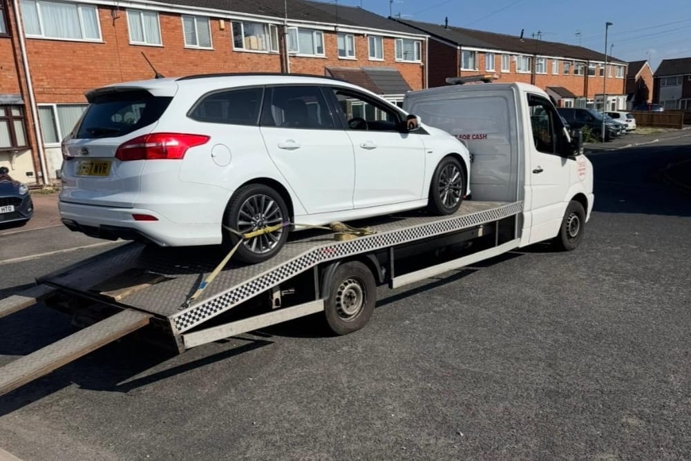White estate car secured on a flatbed tow truck for breakdown recovery