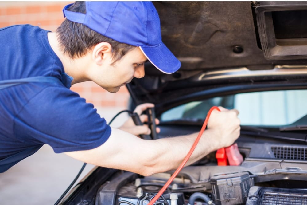 Professional technician connects jumper cables for reliable battery jump start services