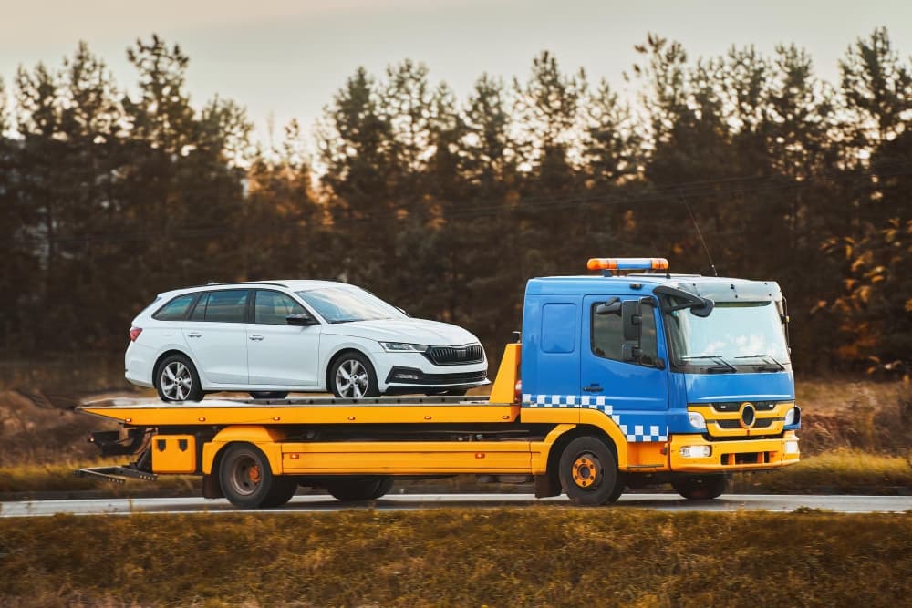 A yellow tow truck transports a white estate car after a breakdown in West Bromwich
