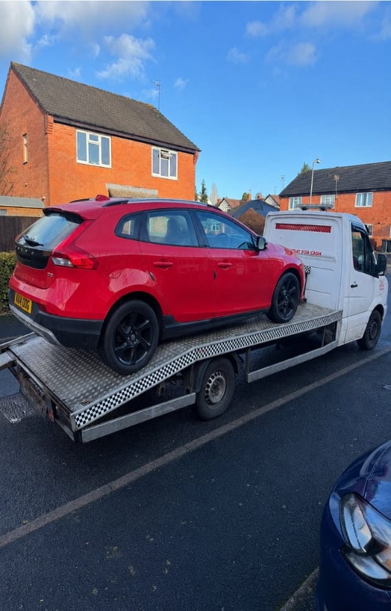 A white flatbed tow truck provides car breakdown recovery for a red Volvo
