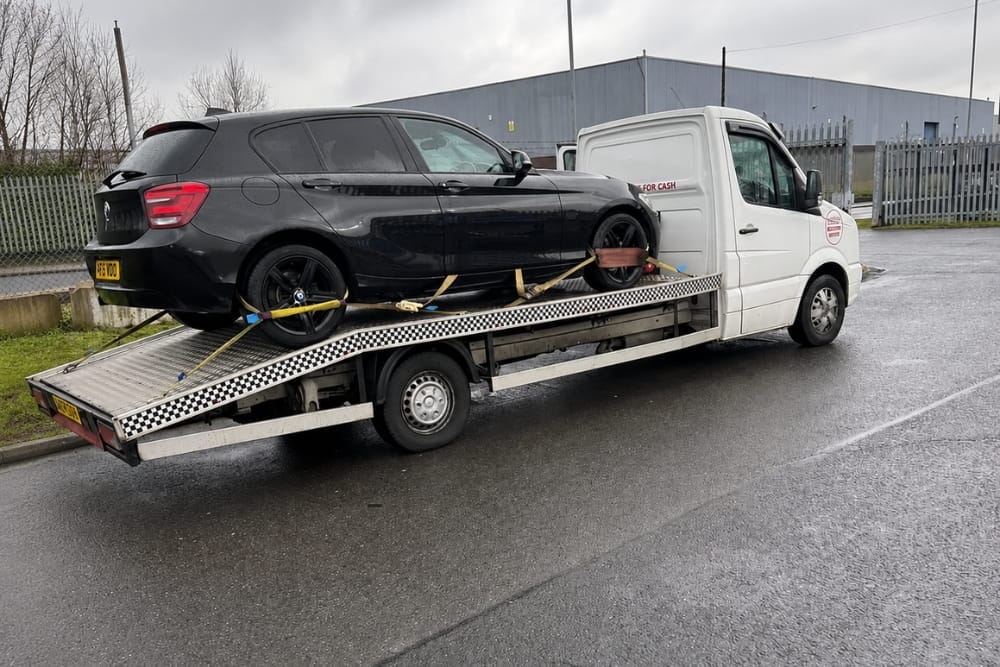 Black car secured on a flatbed tow truck providing accident recovery
