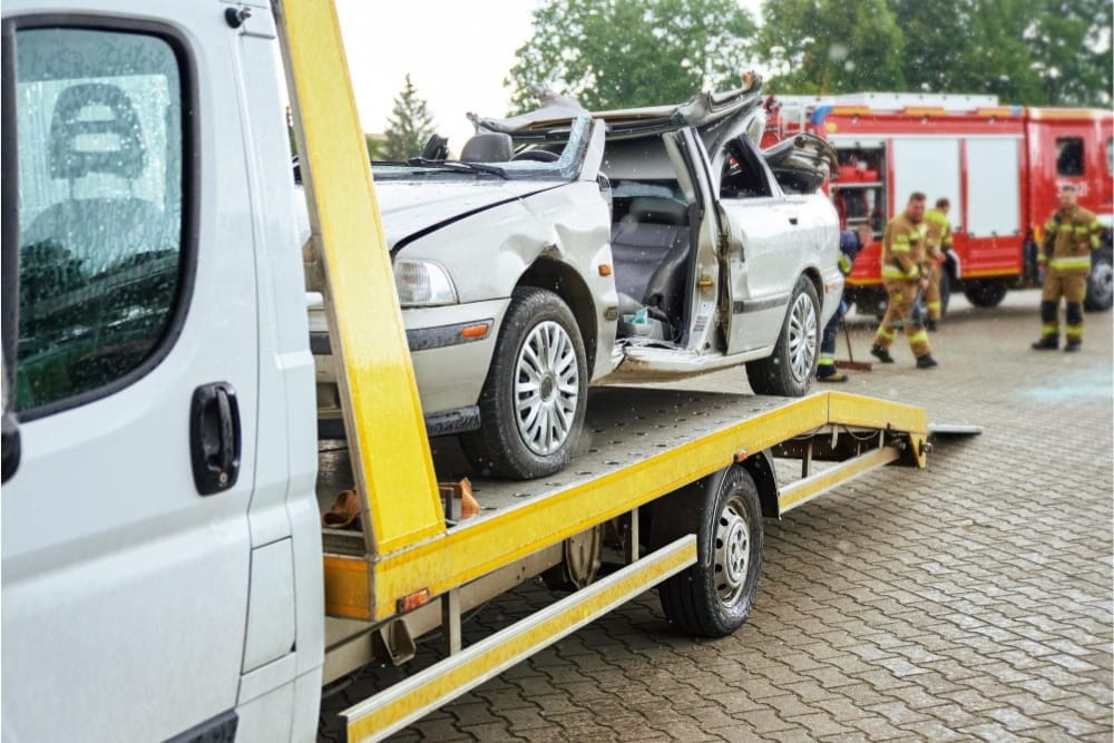 A flatbed truck utilizes a van commercial vehicle recovery service for a wrecked silver car
