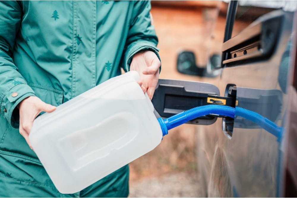Close-up of roadside fuel delivery using a white jerrycan and blue nozzle