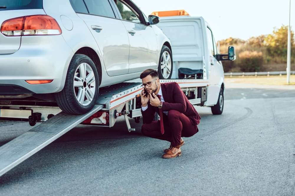 Man calls car breakdown recovery services Erdington beside loaded tow truck